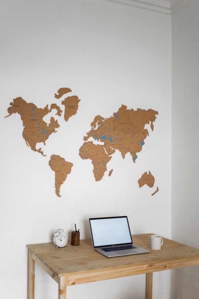 Minimalist workspace featuring a laptop, world map wall decor, and wooden desk.